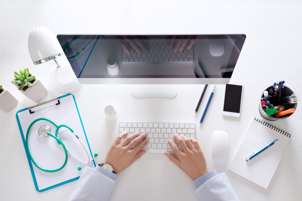Top view of doctor sitting at the desk and using computer